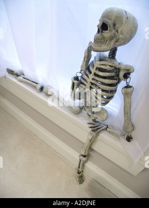 Skelett sitzt auf der Fensterbank Stockfoto