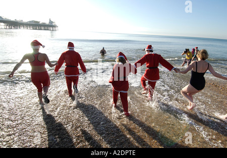 Hardy Schwimmer in Santa Anzüge gekleidet beteiligen sich an der jährlichen Christmas Day-Bad im Meer an Brighton an einem sonnigen Morgen Xmas Stockfoto