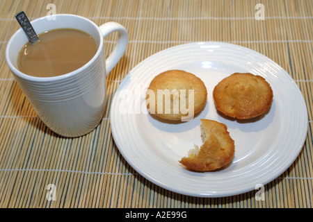 Drei hausgemachte Kuchen auf einem weißen Teller und eine Tasse Kaffee Stockfoto
