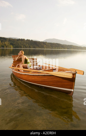 Junge Frau sitzt auf Ruderboot im See Stockfoto