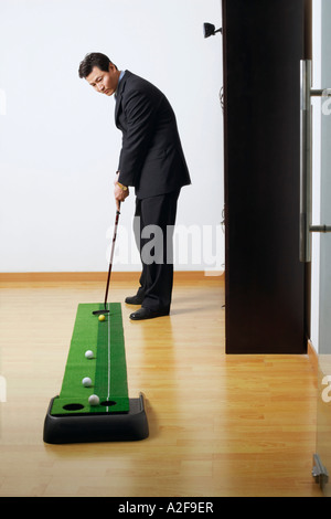 Seitenansicht eines Geschäftsmannes üben Golf in einem club Stockfoto