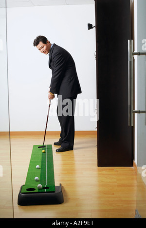 Seitenansicht eines Geschäftsmannes üben Golf in einem club Stockfoto