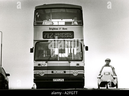 Ein mürrischer konfrontiert Mann in a Sinclair C5-Elektro-Auto, mit dem Bus überholt. Stockfoto