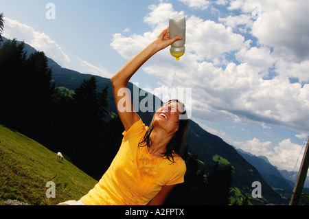 Junge Frau gießt Wasser aus der Flasche im Gesicht Stockfoto