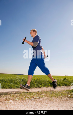 Junger Mann Joggen, Hanteln tragen Stockfoto