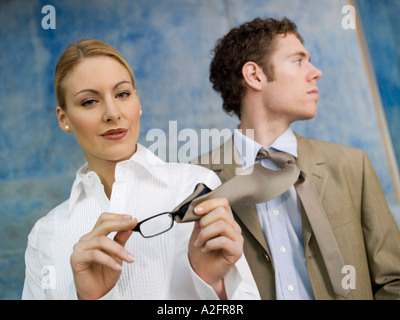 Geschäftsfrau, die Reinigung von Brillen mit Mannes Krawatte Stockfoto