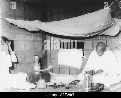 MKG33125 Mahatma Gandhi bei schwachem Licht der Petroleumlampe sitzen unter Moskitonetz in Noakhali West Bengal Indien 1946 schreiben Stockfoto