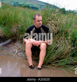 Ein Kandidat sitzt auf der Kante einer schlammigen Graben an der Welt Bog Schnorcheln Meisterschaften in Llanwrtyd Wells Powys Wales UK KATHY DEWITT Stockfoto