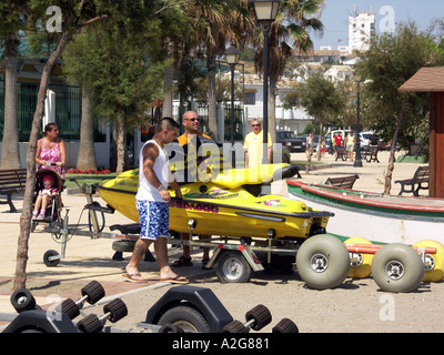 Männer schieben Jet Ski auf einem Wagen über den Strand, La Cala de Mijas, Mijas Costa, Costa Del Sol, Spanien, Europa, Stockfoto