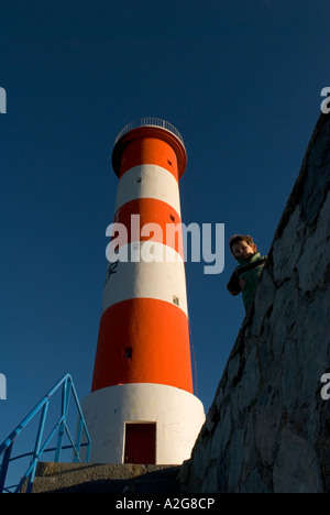 einem niedrigen Winkel Foto der rotweiße Leuchtturm mit kleinen Jungen im Vordergrund Stockfoto