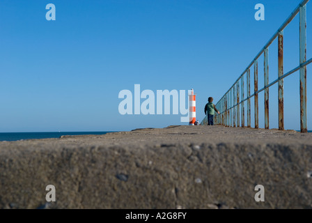 einem niedrigen Winkel Foto der rotweiße Leuchtturm mit kleinen Jungen im Vordergrund Stockfoto