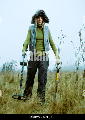 1212968 Outdoor-Tag im Herbst Frau junge 25 30 blonde Wiese Feld Rasen Stand aussehen Weste blau Handschuh Handschuhe weiß golf Stockfoto