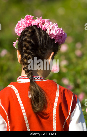 Junge Frau im Bereich der Rosenbusch gekleidet in traditionellen bulgarischen Volkstracht Ernte Rosenblüten beim Rosenfest Stockfoto