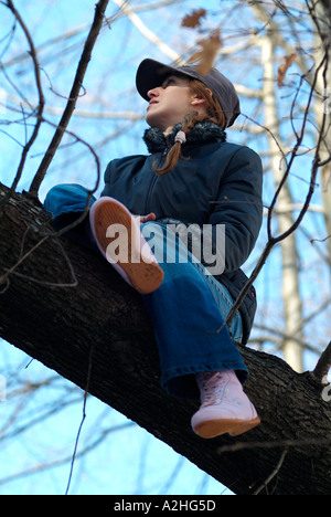 Junge Frau saß in einem Baum Stockfoto