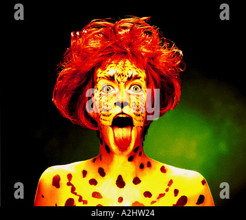 Frau malte Alter 20-25 mit ihrem Gesicht als ein Tiger. Sie trägt eine rote Perücke und hat ihr die Zunge heraus. Stockfoto