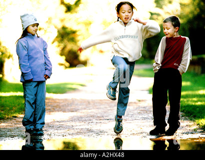 3 Kinder im Alter von 6-8 spielen in einem Park, 2 Mädchen und 1 ist ein Junge. Stockfoto