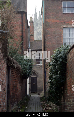 Der Turm der St. Marys Church, Warwick, Blick durch eine Lücke in einigen Bürgerhäusern Zentrum. Eine Tür ist am Ende einer Gasse Stockfoto