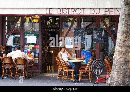 Le Bistrot du Peintre Café Bar Terrasse draußen sitzen auf dem Bürgersteig. Ein junger Mann sitzt alleine auf einem Korbstuhl an einem Tisch mit einem Glas Bier die Bistrot du Peintre ist ein altmodischer Paris Café Café Bar Restaurant des Jugendstil-Design mit poliertem Messing, spiegeln und alte Schilder Stockfoto