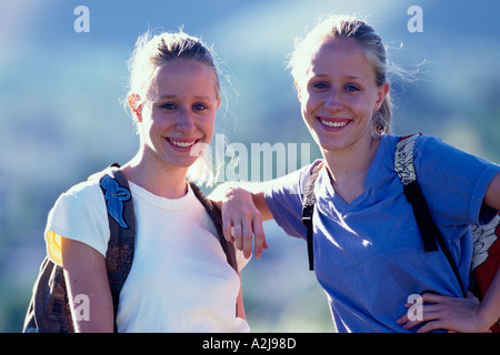 Porträt von zwei lächelnde Schwestern im Freien stehen und tragen bunte Rucksäcke Stockfoto