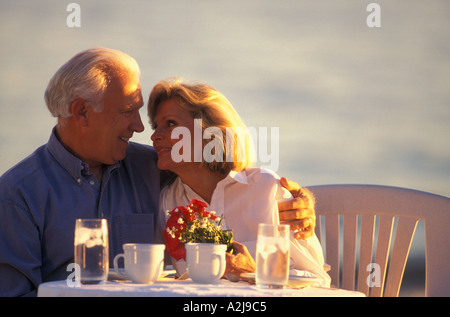 Älteres Paar, umarmen, wie sie lässig leichte Mahlzeiten im Freien sitzen Stockfoto