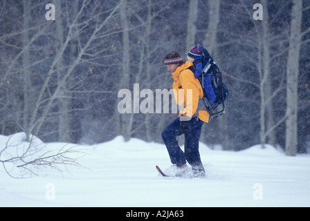 Eine Mutter trägt ihr Baby in einem Rucksack-Träger, wie sie durch ein Feld an einem verschneiten Tag Schneeschuhe Stockfoto