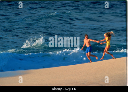 Badeanzug tragen paar laufen hand in hand auf einen Strand zum Meer hin Stockfoto