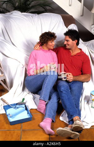 Spaß paar in den 30ern zu Hause im Wohnzimmer mit Kaffee, wie sie arbeiten gemeinsam malen und Entspannung Stockfoto