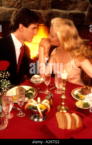 Romantisches Paar gekleidet schön und elegant im Resort vor Kamin mit teuren Abendessen Stockfoto