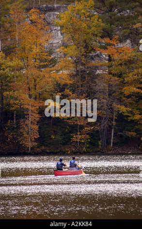 Kanufahrt auf einem Vermont-See mit fallen farbige Blätter auf den Bäumen im Hintergrund Stockfoto