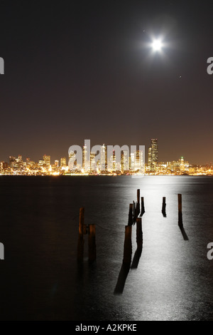 Full Moon Rising über Seattle Stadt Skyline bei Nacht Pilings Silhouette von Mondlicht spiegelt sich in Elliot Bay Seattle Washington Stockfoto