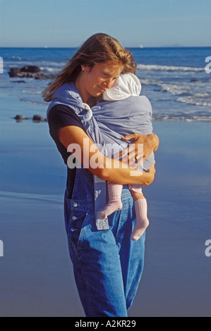 Eine neue Mutter Liebkosungen ihrer kleinen Tochter, während sie am Strand in Santa Barbara Kalifornien entlang geht Stockfoto