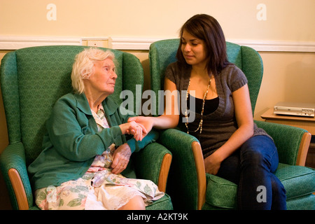 junge Mädchen/Teenager /care Arbeitskraft Besuch sehr alte Dame / Großmutter im Pflegeheim Stockfoto