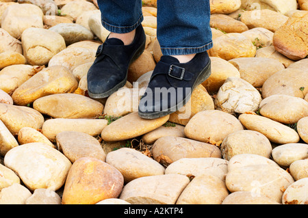 Eine Person, zwei Füße, stehend auf der typische Boden in Chateauneuf, Kieselsteine große Stein genannt Galet Galets Château de Beaucastel, Domaines Perrin, Courthézon Courthézon Vaucluse Frankreich Europa Stockfoto