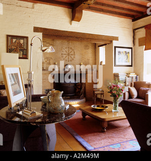 Offener Kamin mit Holzofen im Wohnzimmer mit Holzbalken an den Decken Stockfoto