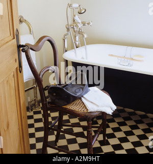 Waschzeug und Handtuch auf Stuhl im Bad mit karierten Bodenfliesen Stockfoto