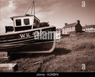 Monochromes Bild Fischerbootes sitzt hoch und trocken unter Häuser in den Hafen von Wick Nordschottland getönt Stockfoto