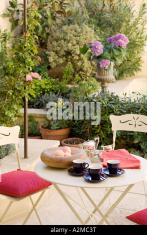 Tabelle mit Tassen und Obstschale gesetzt auf einer Veranda im freien Stockfoto