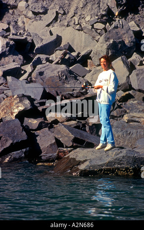 Frau, die Fischerei auf Lachs aus Felsen Seward Alaska USA Stockfoto