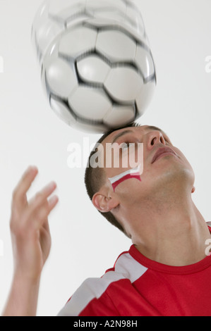 Nahaufnahme des Menschen Ausgleich Fußball Ball auf dem Kopf Stockfoto