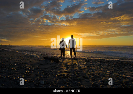 Paar Wachen die untergehende Sonne über der Tasmansee in Greymouth auf der neuseeländischen Südinsel. Stockfoto