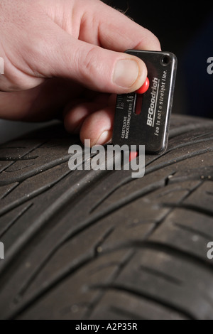 Kontrolle der Reifen-Lauffläche mit einem Messwerkzeug Stockfoto