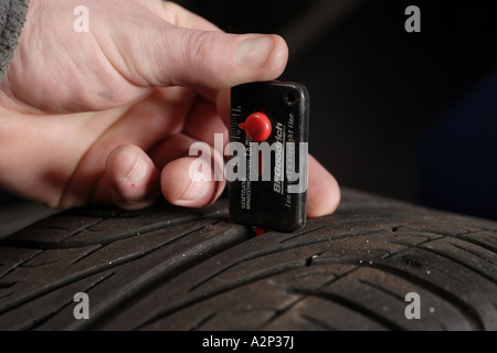Kontrolle der Reifen-Lauffläche mit einem Messwerkzeug Stockfoto