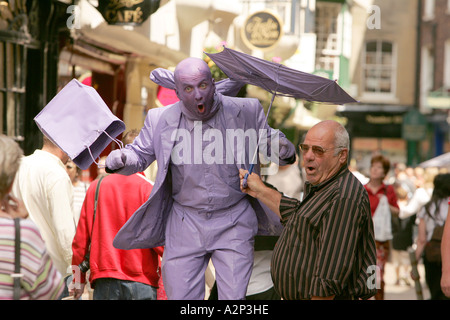 MIME-Künstler Schauspieler Straßenkünstler in Kostüm-Theater-Interpreten unterhalten Touristen, die lila Farbe Körper Regenschirm Menschen gehen Stockfoto