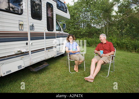 Älteres Paar sitzt neben einem Wohnwagen Stockfoto