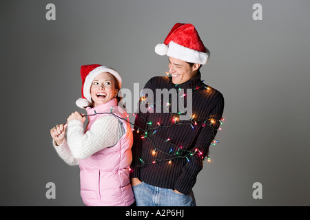 Frau zieht Mann gefesselt in Weihnachtsbeleuchtung Stockfoto