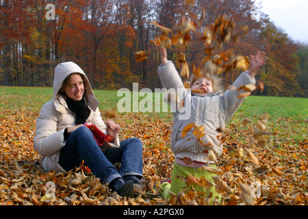 Mädchen spielen im Herbstlaub Stockfoto