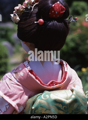 Mädchen in Maiko Lehrling Geisha Kostüm im japanischen Garten von Gion Kyoto tragen Kimono Obi Perücke Sonnenschirm Make-up Lippenstift Stockfoto