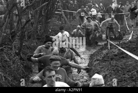 Wettbewerber waten in kaltem schlammigen Strom Tough Guy Rennen bei Tettenhall, West Midlands, England, UK Stockfoto