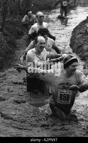 Wettbewerber waten in kaltem schlammigen Strom Tough Guy Rennen bei Tettenhall, West Midlands, England, UK 1991 Stockfoto