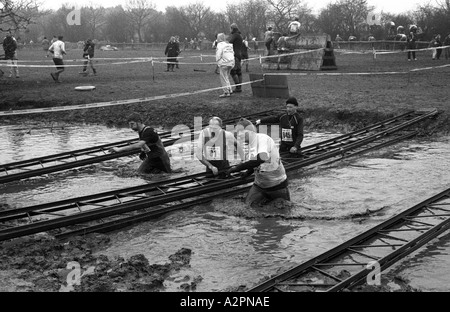 Wettbewerber waten durch kaltes Schmutzwasser Tough Guy Rennen bei Tettenhall, West Midlands, England, UK 1991 Stockfoto